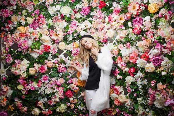 Unga vackra blonda kvinnan i fashionabla hatt på blommig bakgrund — Stockfoto