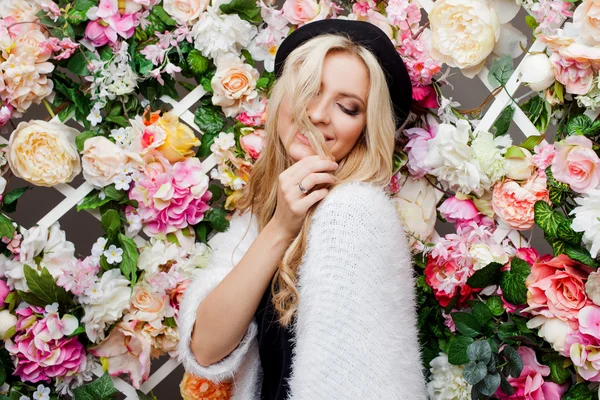 Молодая красивая блондинка в модной шляпе на цветочном фоне — стоковое фото