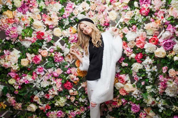 Junge schöne blonde Frau in modischen Hut auf floralem Hintergrund — Stockfoto