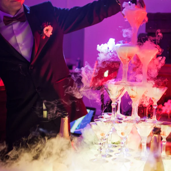 Casal estão derramando champanhe na pirâmide de copos, no restaurante — Fotografia de Stock
