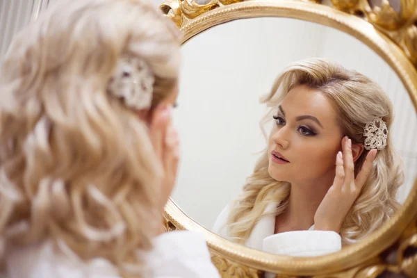 Portrait of young sexy woman in a white dress looking at the mirror. Stock Photo