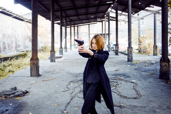 Mujer apuntando con un arma. Mafia chica disparando a alguien en la calle . — Foto de Stock