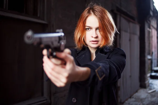 Woman pointing a gun. Mafia girl shooting at someone on the street. Emotion of fear, fright — Stock Photo, Image