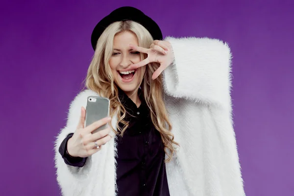 Chica joven de moda tomando fotos de sí misma, selfie. Fondo púrpura —  Fotos de Stock