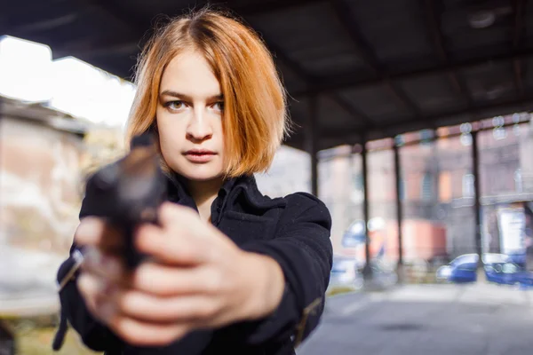 Mulher a apontar uma arma. Mafia menina atirando em alguém na rua . — Fotografia de Stock