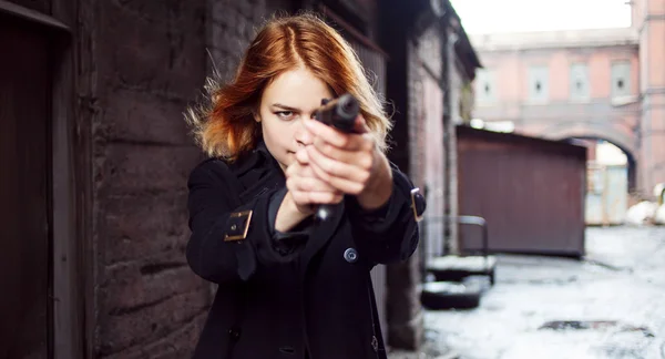 Γυναίκα δείχνει ένα πυροβόλο όπλο. Κοπέλα μαφία γυρίσματα σε κάποιον στο δρόμο. — Φωτογραφία Αρχείου