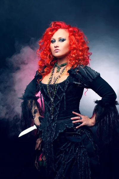 La Strega di Halloween crea magia. Donna attraente con i capelli rossi in costume streghe — Foto Stock