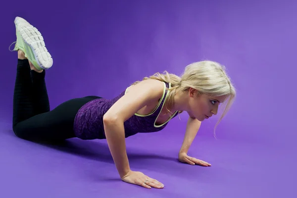 Mujer joven haciendo ejercicios push-ups fitness en el estudio — Foto de Stock