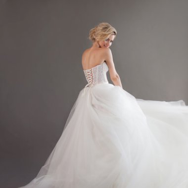 Lüks gelinlik büyüleyici genç gelin. Güzel kız beyaz, gri arka planda, metniniz sağ için yer