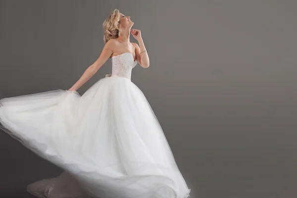 Charmante junge Braut im luxuriösen Hochzeitskleid. hübsches Mädchen in weiß, grauer Hintergrund, rechts Platz für Ihren Text — Stockfoto