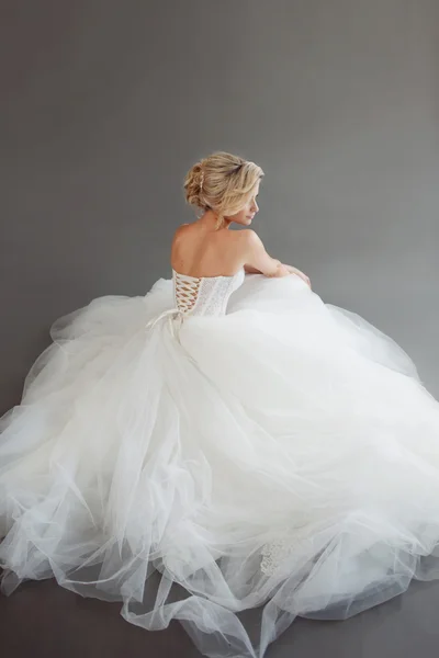 Encantadora joven novia en vestido de novia de lujo. Una chica guapa de blanco. Fondo gris. Atrás —  Fotos de Stock