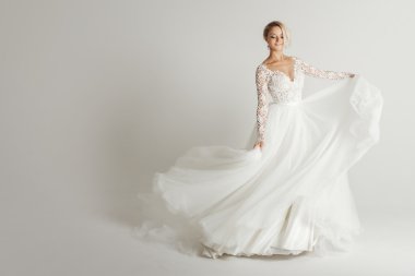 Güzel çekici gelin gelinlik uzun tam etek, beyaz arka plan ile dans ve gülümse