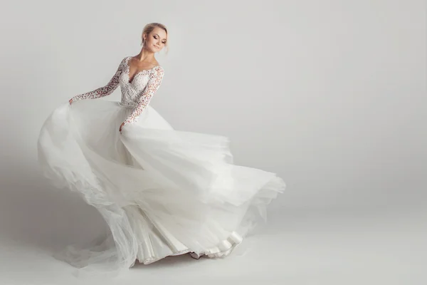 Όμορφη ελκυστική νύφη στο γάμο φόρεμα με μακριά φαρδιά φούστα, λευκό φόντο, χορού και το χαμόγελο — Φωτογραφία Αρχείου