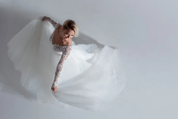 Beautiful attractive bride in wedding dress with long full skirt, white background, dance and smile, top view — Stock Photo, Image