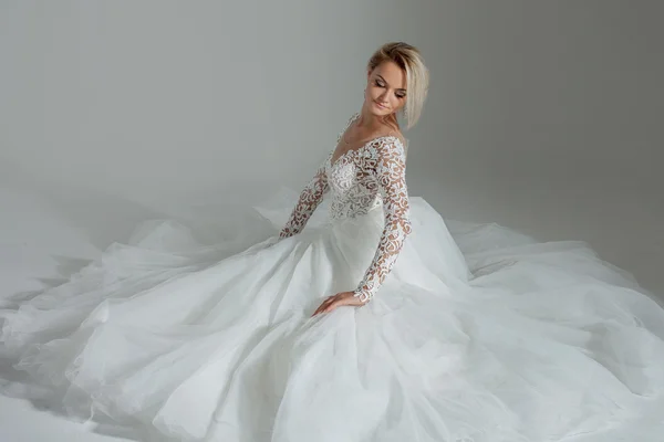 Schöne Braut in luxuriösem Hochzeitskleid, sitzend im Kreis lange Röcke. weißer Hintergrund, Draufsicht — Stockfoto