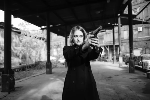 Kvinna som pekar en pistol. Maffian flicka skytte på någon på gatan. — Stockfoto