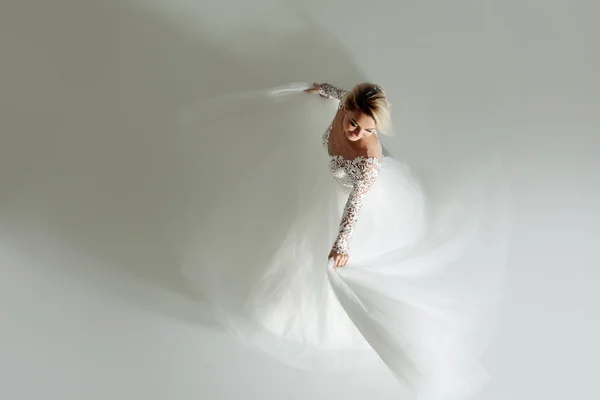 Schöne attraktive Braut im Brautkleid mit langem Rock, weißem Hintergrund, Tanz und Lächeln, Draufsicht — Stockfoto