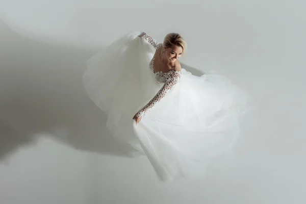 Hermosa novia atractiva en vestido de novia con falda larga y completa, fondo blanco, danza y sonrisa, vista superior — Foto de Stock