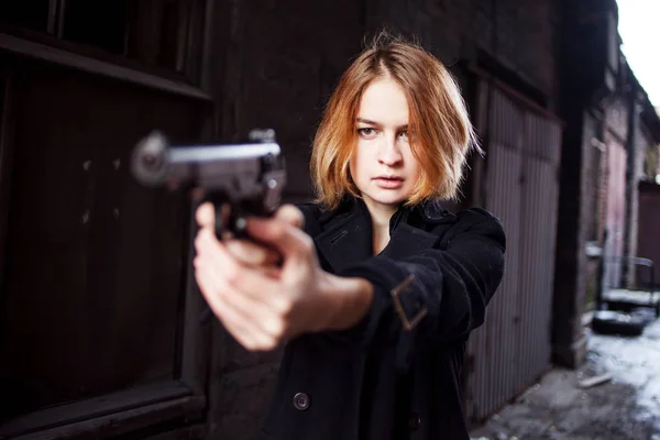 Γυναίκα δείχνει ένα πυροβόλο όπλο. Κοπέλα μαφία γυρίσματα σε κάποιον στο δρόμο. — Φωτογραφία Αρχείου
