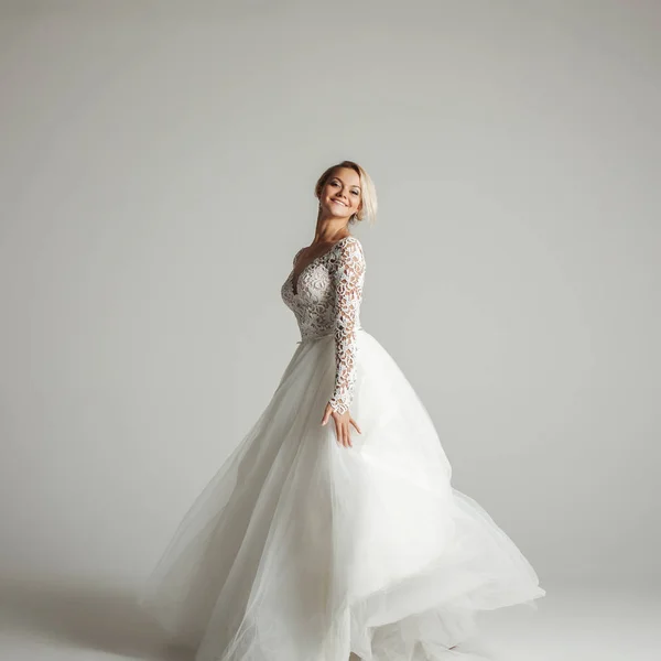 美丽的吸引力新娘穿着婚纱时有长时间充分的裙子，白色背景，跳舞和微笑 — 图库照片