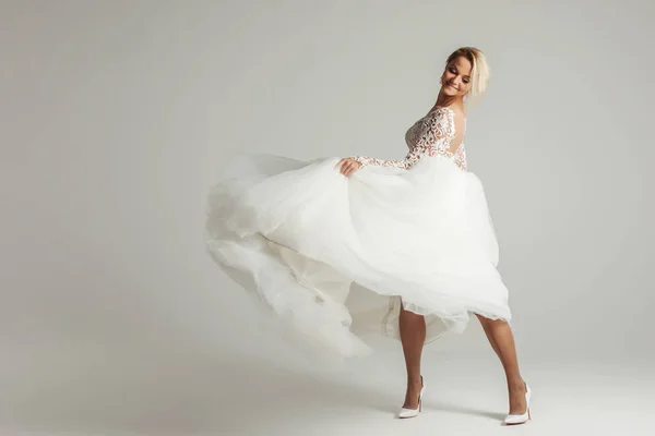 Schöne attraktive Braut im Brautkleid mit langem Rock, weißem Hintergrund, Tanz und Lächeln — Stockfoto