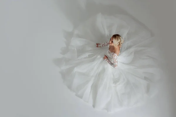 Красивая невеста в роскошном свадебном платье, сидя в круге длинные юбки. Белый фон, вид сверху — стоковое фото