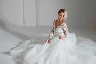 güzel gelin lüks gelinlik, daire uzun etekle oturuyor. Beyaz arka plan, üstten görünüm