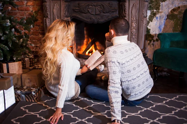 Par avkopplande hemma läser en bok. Fot i ull strumpor nära eldstaden. Vinter semester koncept — Stockfoto