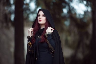 Genç güzel ve gizemli kadın ormanda hood, orman elf ya da cadı görüntü ile siyah pelerin
