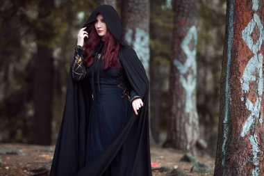 Genç güzel ve gizemli kadın ormanda hood, orman elf ya da cadı görüntü ile siyah pelerin