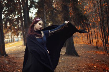 Genç güzel ve gizemli kadın ormanda hood, orman elf ya da cadı görüntü ile siyah pelerin