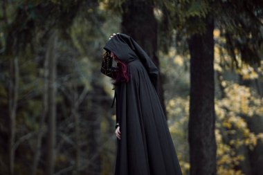 Genç güzel ve gizemli kadın ormanda hood, orman elf ya da cadı görüntü ile siyah pelerin