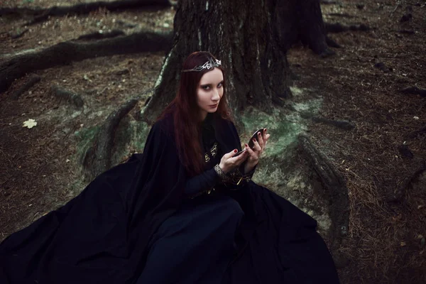 Молодая красивая и загадочная женщина изображает лесного эльфа или ведьму, смотрящую в зеркало — стоковое фото