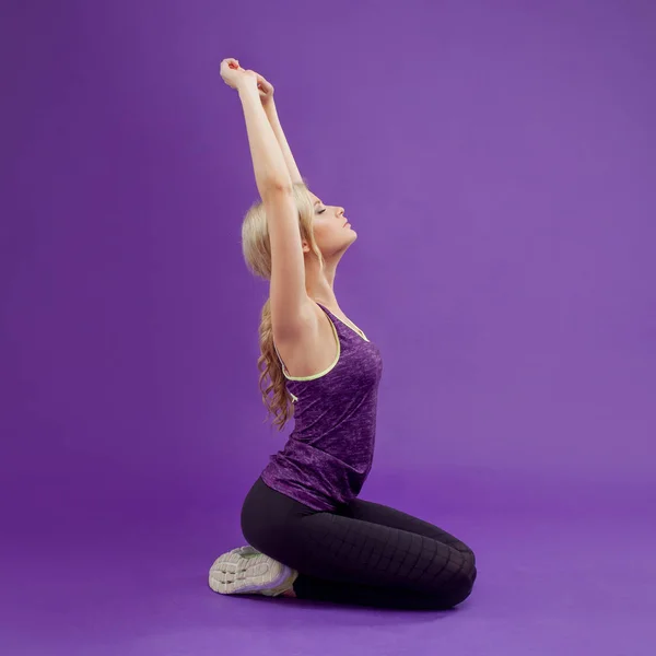 Yoga pose. Young sporty women on a purple background. Exhales, pulls hands up — Stock Photo, Image