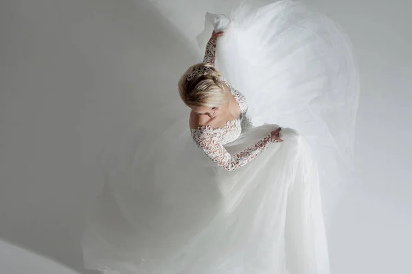 Linda noiva atraente em vestido de noiva com saia longa e cheia, fundo branco, dança e sorriso, vista superior — Fotografia de Stock
