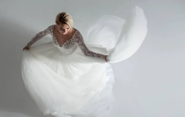 Belle mariée attrayante en robe de mariée avec jupe longue pleine, fond blanc, danse et sourire, vue sur le dessus — Photo