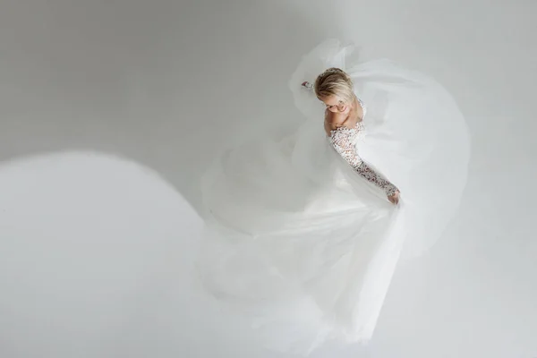 Hermosa novia atractiva en vestido de novia con falda larga y completa, fondo blanco, danza y sonrisa, vista superior — Foto de Stock