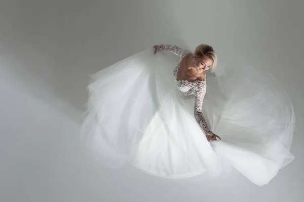 Gyönyörű vonzó menyasszony, esküvői ruha, hosszú teljes szoknya, fehér háttér, tánc és mosoly, felülnézet — Stock Fotó