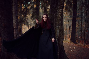 Genç güzel ve gizemli kadın ormanda hood, orman elf ya da cadı görüntü ile siyah pelerin