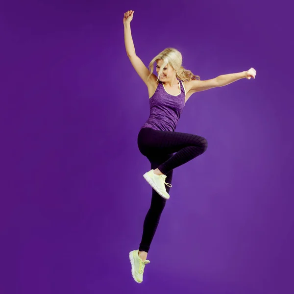 Belle jeune fille dans une pose coureuse. Fond studio, violet. Joyeux saut — Photo