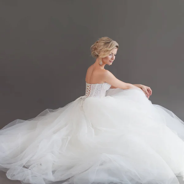 Bájos fiatal menyasszony luxus esküvői ruha. Csinos lány fehér. Szürke háttér. Vissza — Stock Fotó