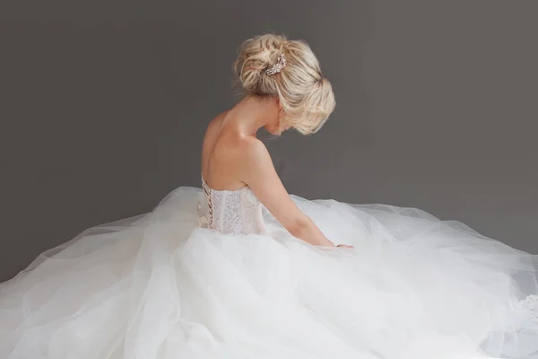 Очаровательная невеста в роскошном свадебном платье. Красивая девушка в белом. Серый фон. Назад — стоковое фото