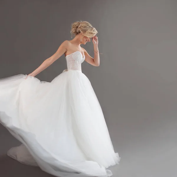 Táncoló fiatal menyasszony luxus esküvői ruha. Csinos lány fehér. Érzelmek, boldogság, nevetés és mosoly, szürke háttér — Stock Fotó
