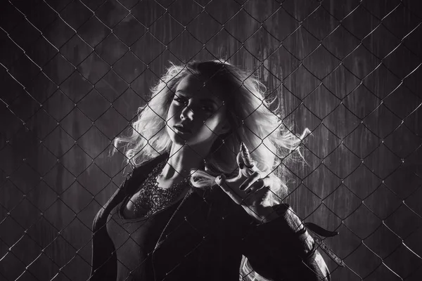 Fuori dalla legge. Attraente bionda femme dietro la rete di recinzione. Tonificante bianco e nero — Foto Stock