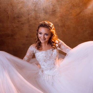 Çok mutlu kız gelin portre altın tonlarda katta oturan lüks gelinlik