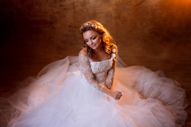 Çok mutlu kız gelin portre altın tonlarda katta oturan lüks gelinlik