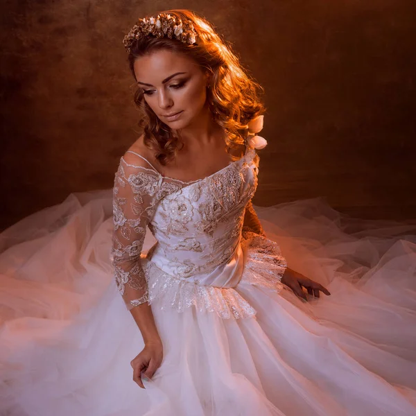 Hermosa novia chica en lujoso vestido de novia sentado en el suelo, retrato en tonos dorados, efectos de deslumbramiento — Foto de Stock