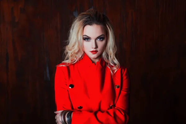 Young and attractive blond woman in red jacket, background grunge rusty wall — Stock Photo, Image