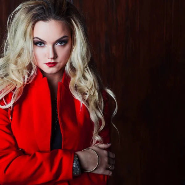 Jovem e atraente mulher loira em casaco vermelho, fundo grunge parede enferrujada — Fotografia de Stock