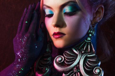 Parlak sanat-makyaj, mor tonlarda genç çekici sarışın kız. Rhinestones ve glitter vücut boyama.